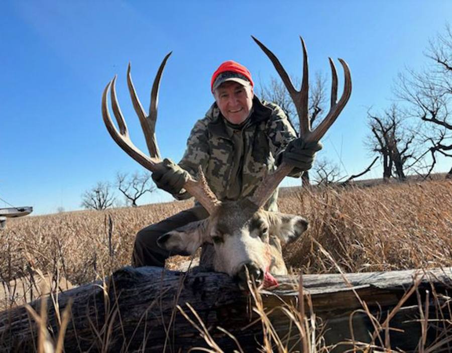 Dakota Safaris hunter kneeling behind a trophy mule deer buck taken along the Cheyenne River