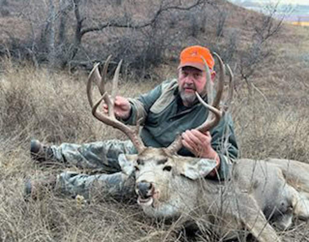 Archery hunter with a mule deer buck